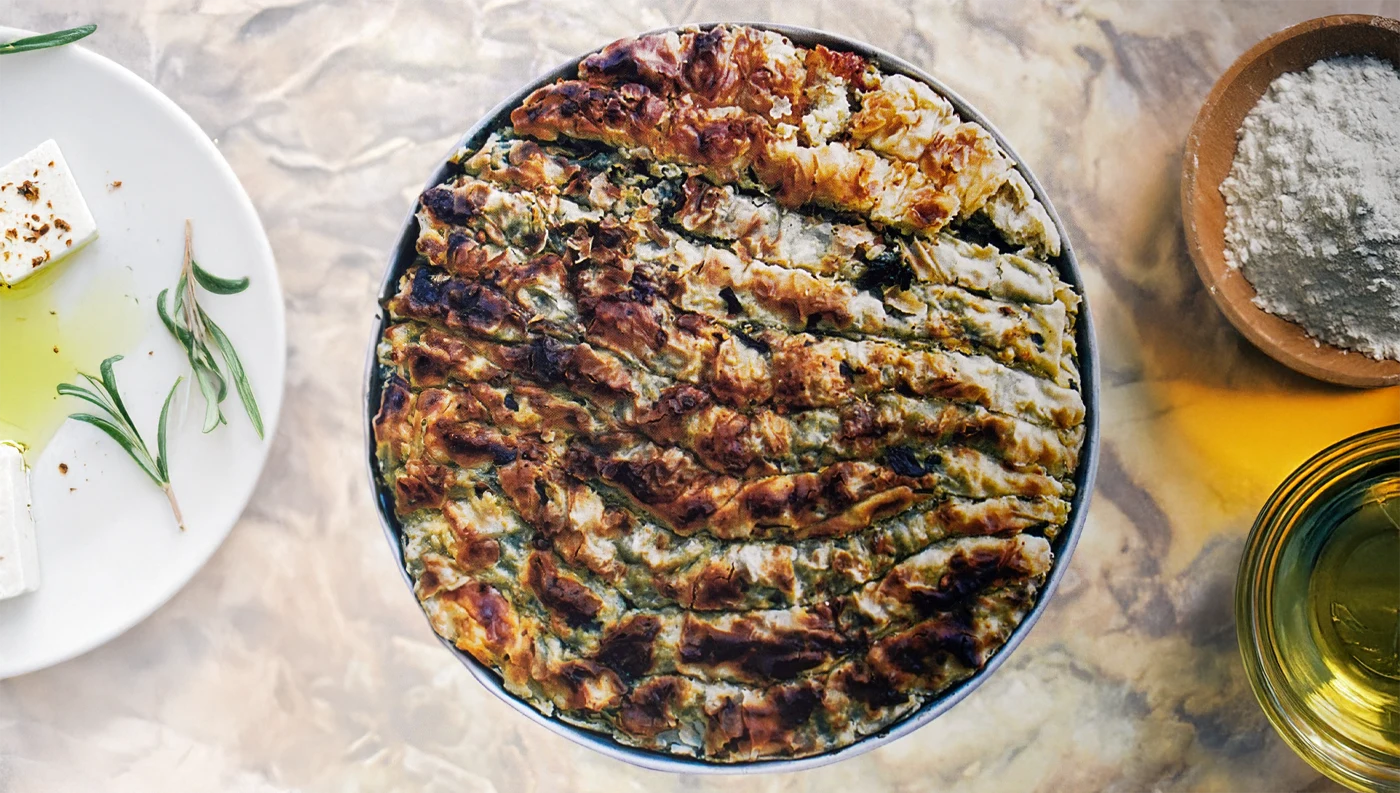 Παραδοσιακή τσουκνιδοπίτα με τραγανό φύλλο, άγρια χόρτα, φέτα και τσουκνίδα σε ξύλινο τραπέζι