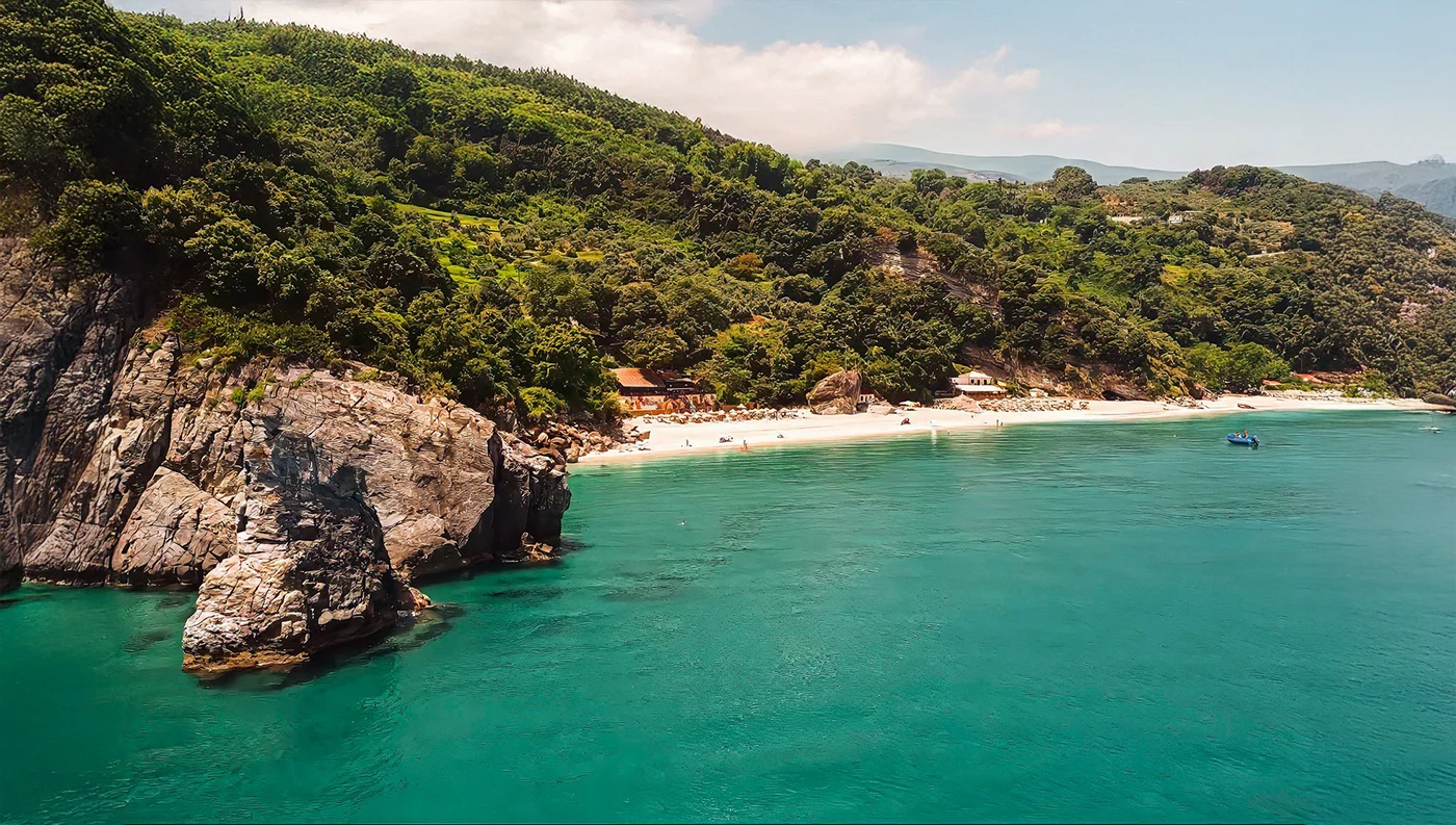 Παραλία Αγίων Σαράντα στο Πήλιο με χρυσή άμμο, ψηλό βράχο και καθαρά γαλαζοπράσινα νερά του Αιγαίου