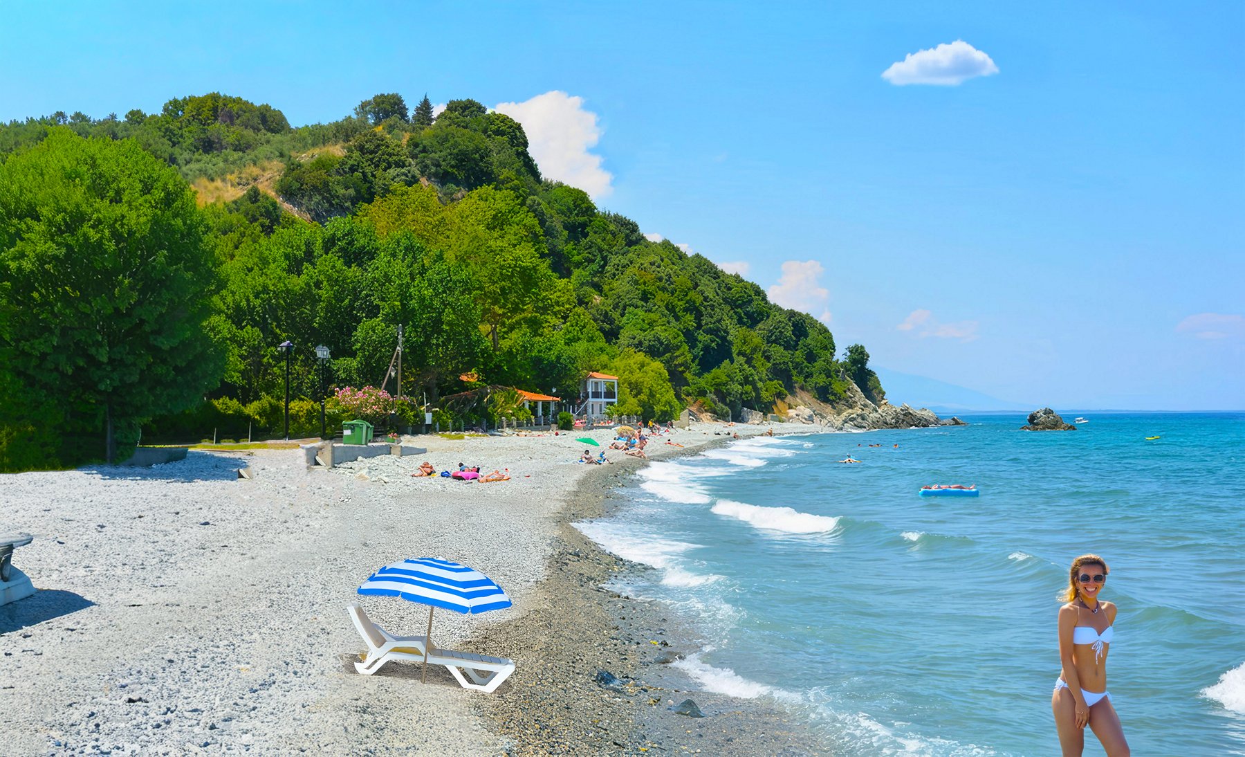 Η παραλία με βότσαλα στο Κόκκινο Νερό Λάρισας, με φόντο το πράσινο τοπίο και λουόμενους στην ακτή