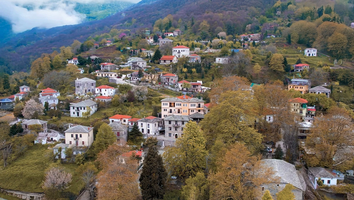 Πανοραμική άποψη του παραδοσιακού οικισμού Κισσός στο Πήλιο, με πέτρινα αρχοντικά και φθινοπωρινά χρώματα.
