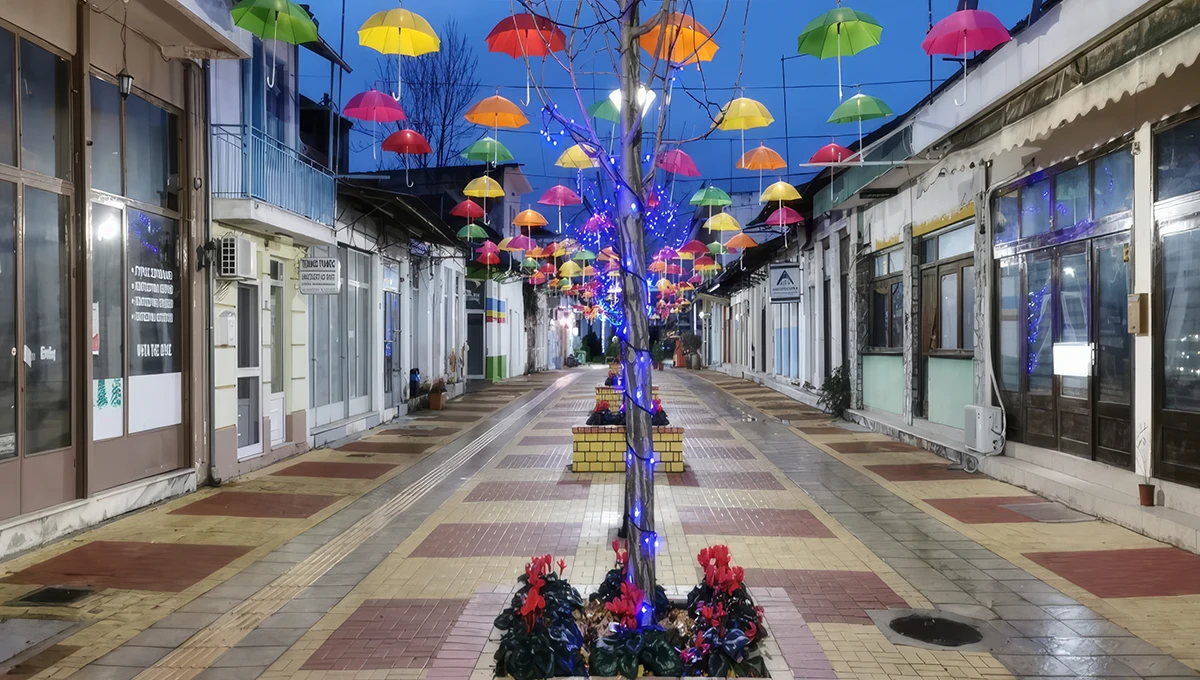 Κεντρικός πεζόδρομος των Σοφάδων με πολύχρωμες ομπρέλες κρεμασμένες ψηλά και φωτισμό τη νύχτα