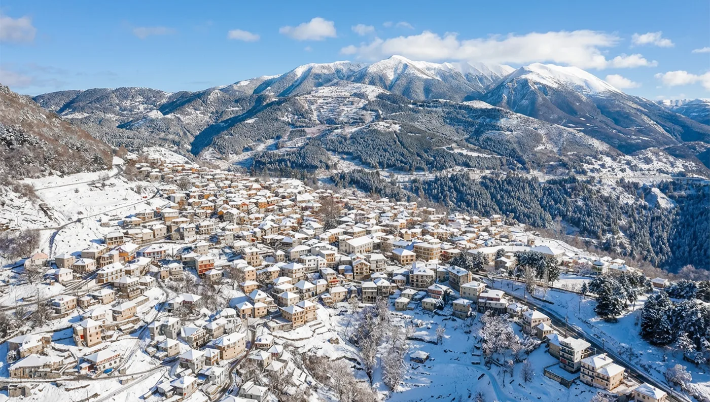 Χιονισμένο Λιβάδι Ολύμπου με πέτρινα σπίτια και ορεινό τοπίο