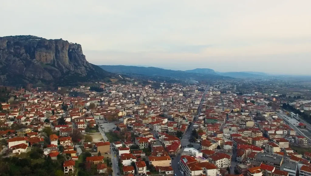 Εναέρια λήψη της πόλης της Καλαμπάκας, με τους εντυπωσιακούς βράχους των Μετεώρων να υψώνονται επιβλητικά στο βάθος.