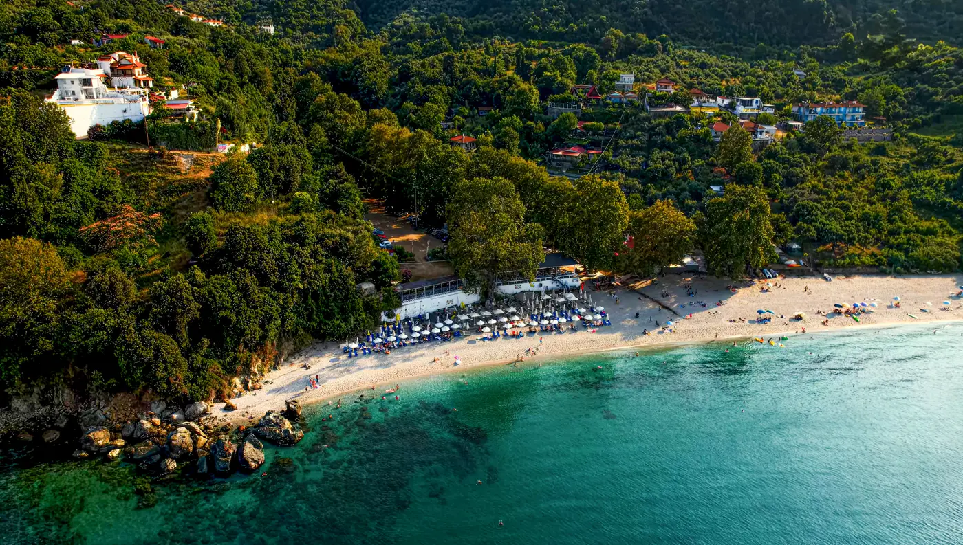 Πανοραμική εναέρια λήψη της παραλίας Πλατιά Άμμος στη Λάρισα, όπου το καταπράσινο βουνό συναντά τα γαλαζοπράσινα νερά.