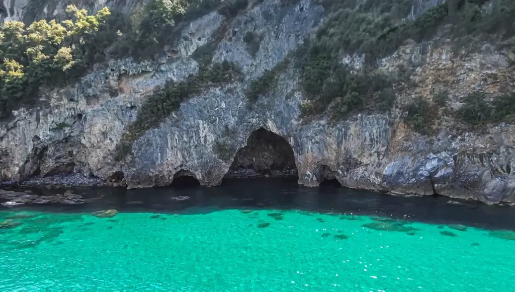 Το εσωτερικό μιας μεγάλης θαλασσοσπηλιάς στο Βένετο Πηλίου, με πρασινογάλαζα νερά και έντονο φως να περνάει από την είσοδο.