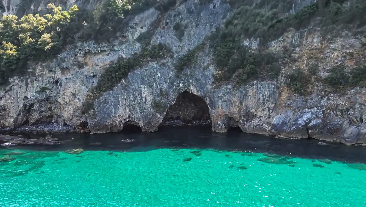 Το εσωτερικό μιας μεγάλης θαλασσοσπηλιάς στο Βένετο Πηλίου, με πρασινογάλαζα νερά και έντονο φως να περνάει από την είσοδο.