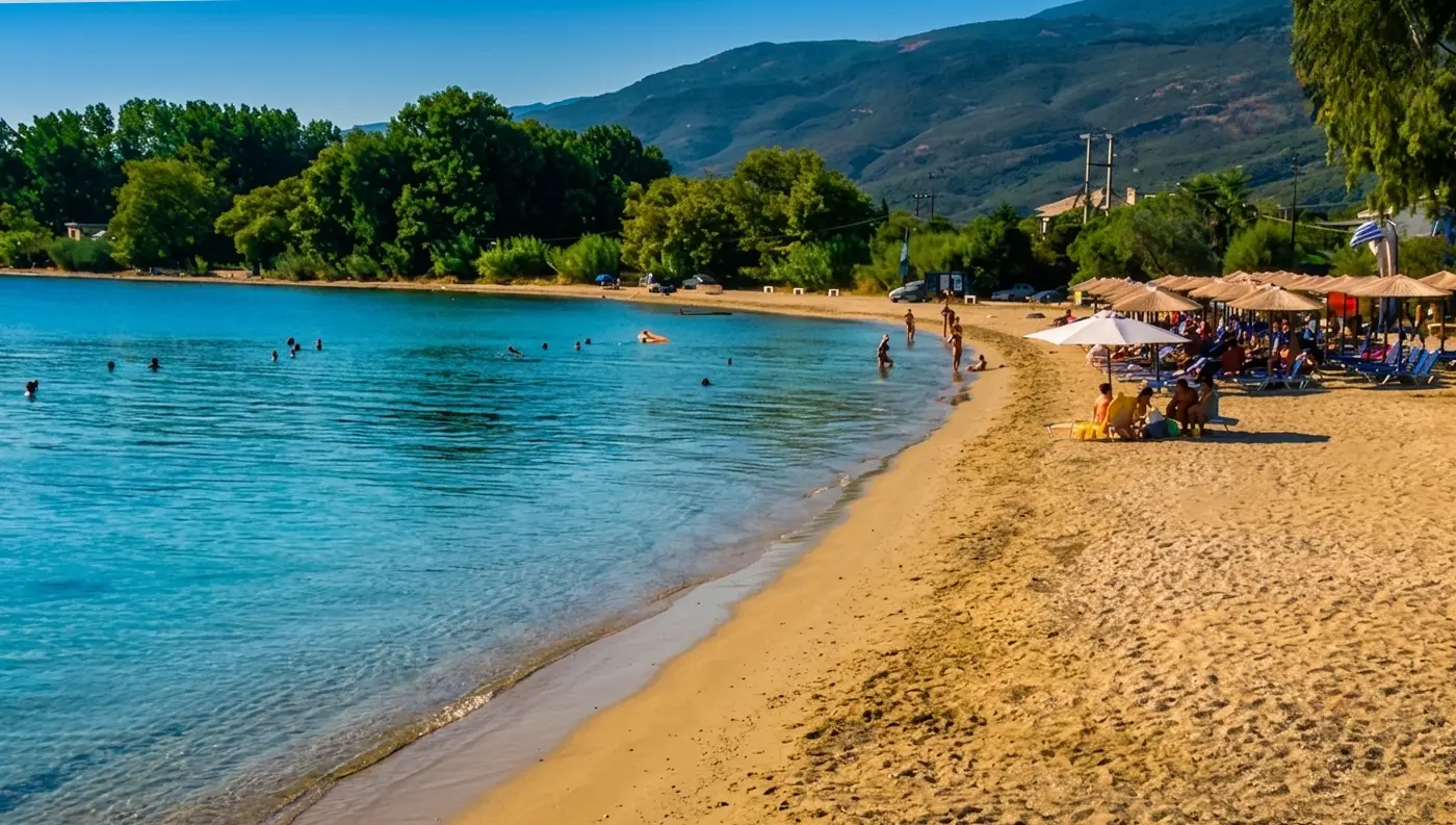 Οικογένειες και λουόμενοι που απολαμβάνουν το μπάνιο τους στα ρηχά και πεντακάθαρα νερά της παραλίας Κορώπη στον Παγασητικό.