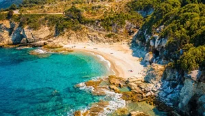 Εναέρια λήψη με drone που δείχνει την παραλία Καλαμάκι στο Πήλιο, με τα γαλαζοπράσινα νερά και τα λευκά βότσαλα.