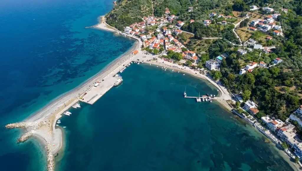 Εναέρια λήψη με τα γαλαζοπράσινα νερά, όπου το Λουτράκι Σκοπέλου φαίνεται χτισμένο αμφιθεατρικά δίπλα στη θάλασσα.
