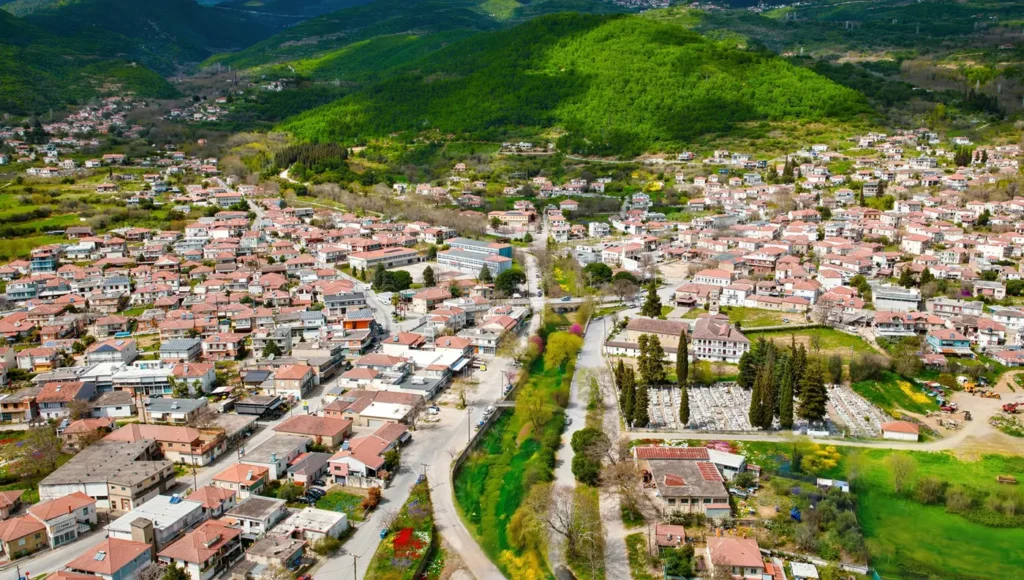 Εναέρια λήψη που δείχνει τα πυκνοχτισμένα σπίτια με τις κόκκινες στέγες στον οικισμό, και στο βάθος τις καταπράσινες πλαγιές της Όσσας.