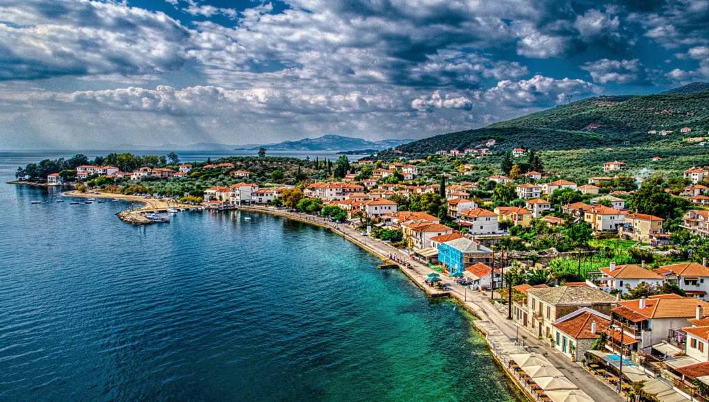 Πανοραμική αεροφωτογραφία που δείχνει την Κάτω Γατζέα Νότιο Πήλιο, με τα παραδοσιακά σπίτια με τις κόκκινες σκεπές χτισμένα κατά μήκος του παραλιακού δρόμου δίπλα στα γαλαζοπράσινα νερά του Παγασητικού.
