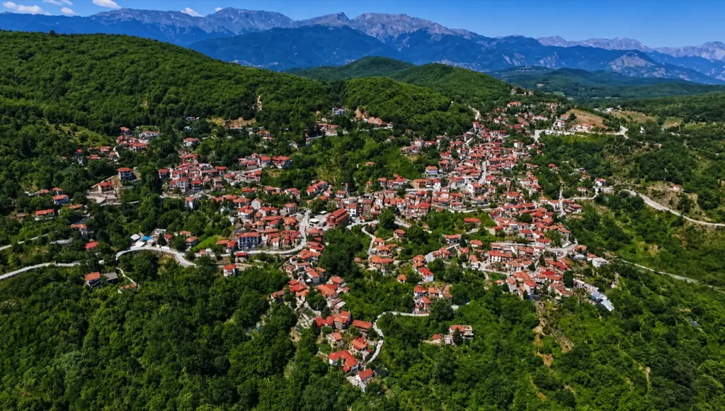 Εναέρια γενική άποψη του χωριού Μορφοβούνι Καρδίτσας, που δείχνει τη μεγάλη έκταση του οικισμού μέσα στο δάσος, με τις κορυφές των Αγράφων να διακρίνονται στο βάθος