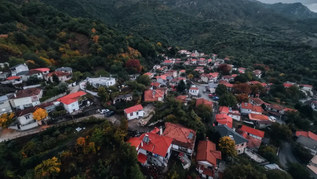 Εναέρια λήψη drone που αποτυπώνει τα σπίτια με τις κόκκινες στέγες στο Ξυλοπάροικο Τρικάλων κάτω από συννεφιασμένο ουρανό.